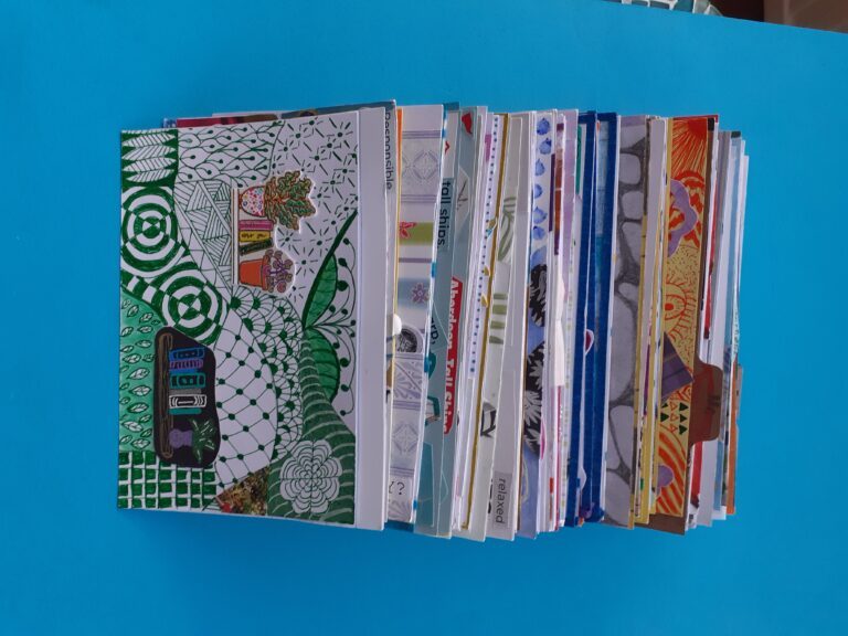 An art journal built of index cards with doodles and collages on.